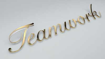 The word 'Teamwork' is written in elegant, gold cursive lettering against a light gray background.