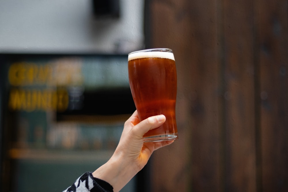 a person holding a glass of beer in their hand