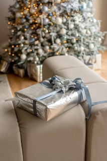 Person unwrapping a beautifully decorated present indoors.