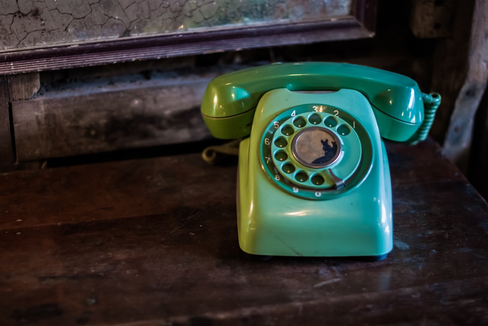 a green phone sitting on top of a wooden table