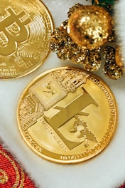 two gold bitcoins sitting next to a christmas tree