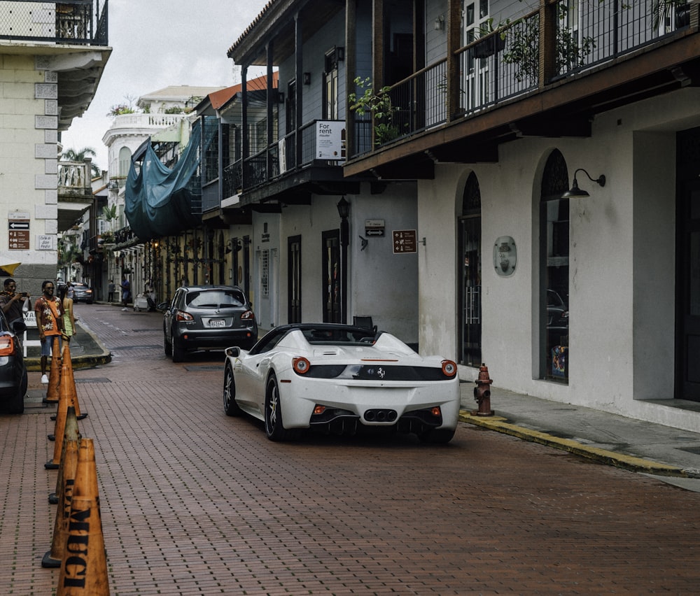 a white sports car parked on the side of a street