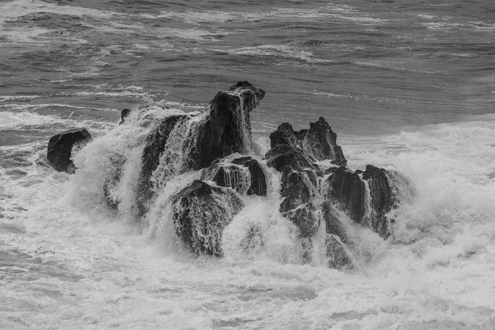 a black and white photo of waves crashing on rocks