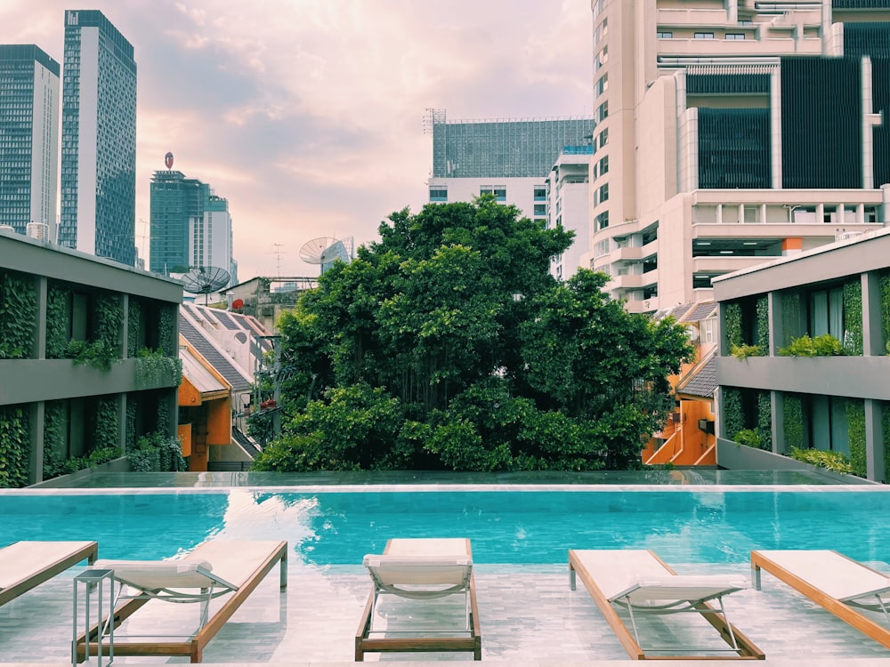 a swimming pool with lounge chairs and trees in the background