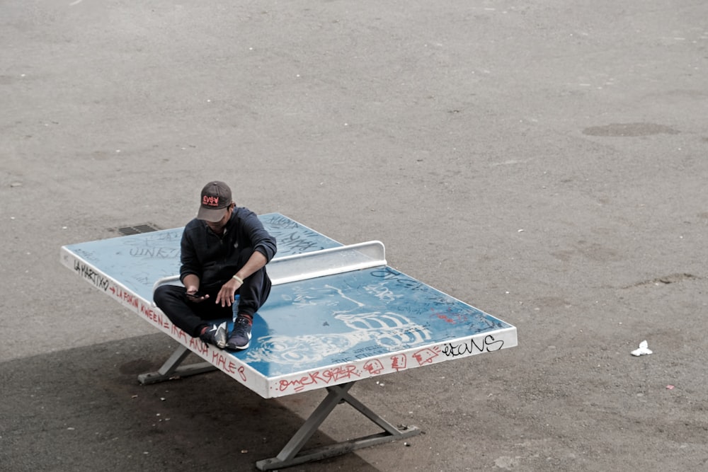 a man sitting on top of a blue table