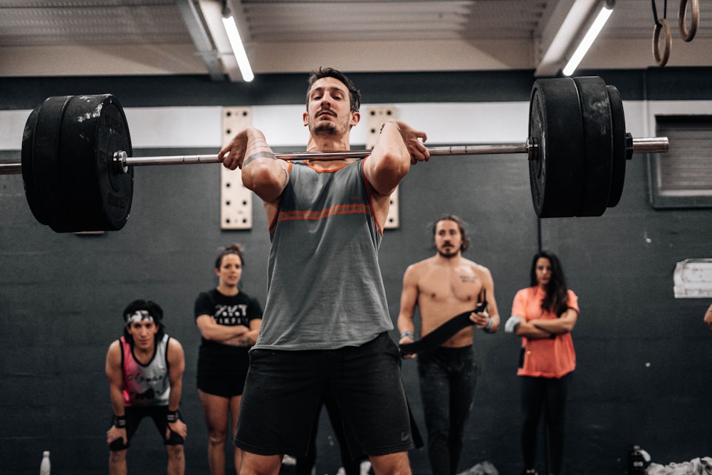 a man lifts a barbell in front of a group of people