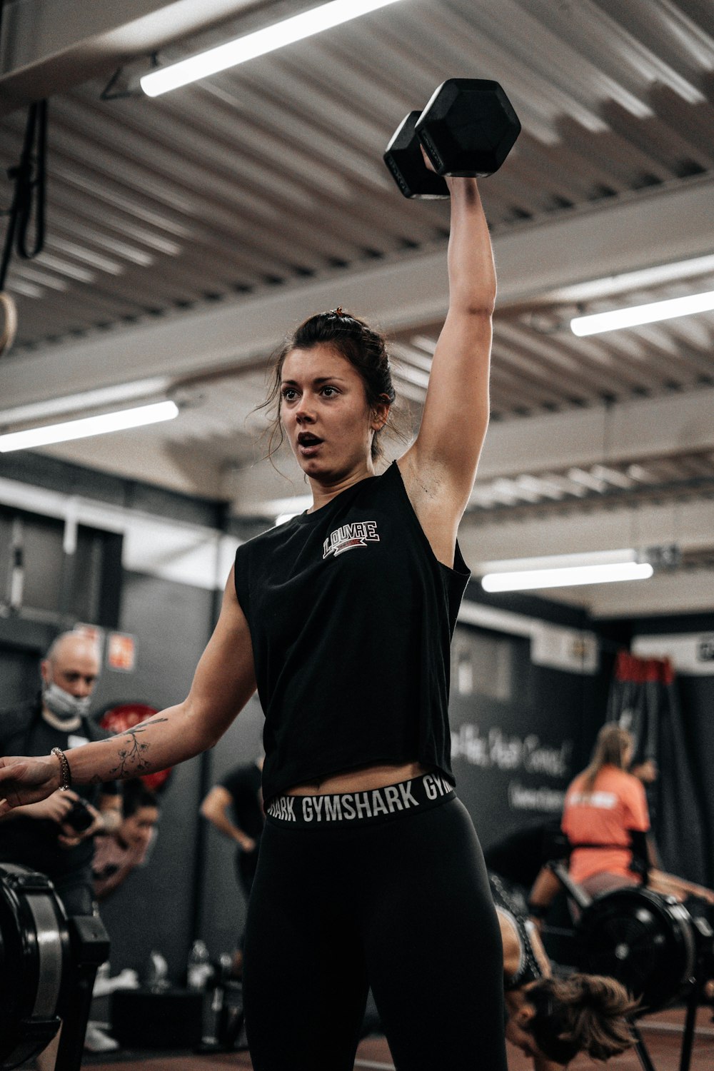 a woman lifting a black dumbbell in a gym