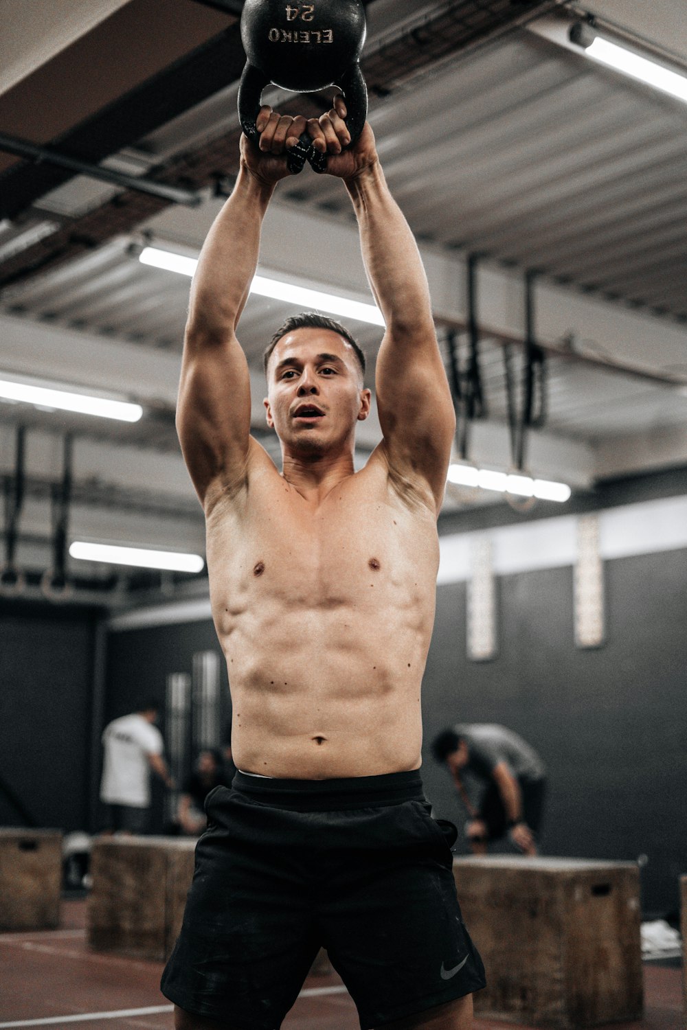 a shirtless man holding a kettle in a gym