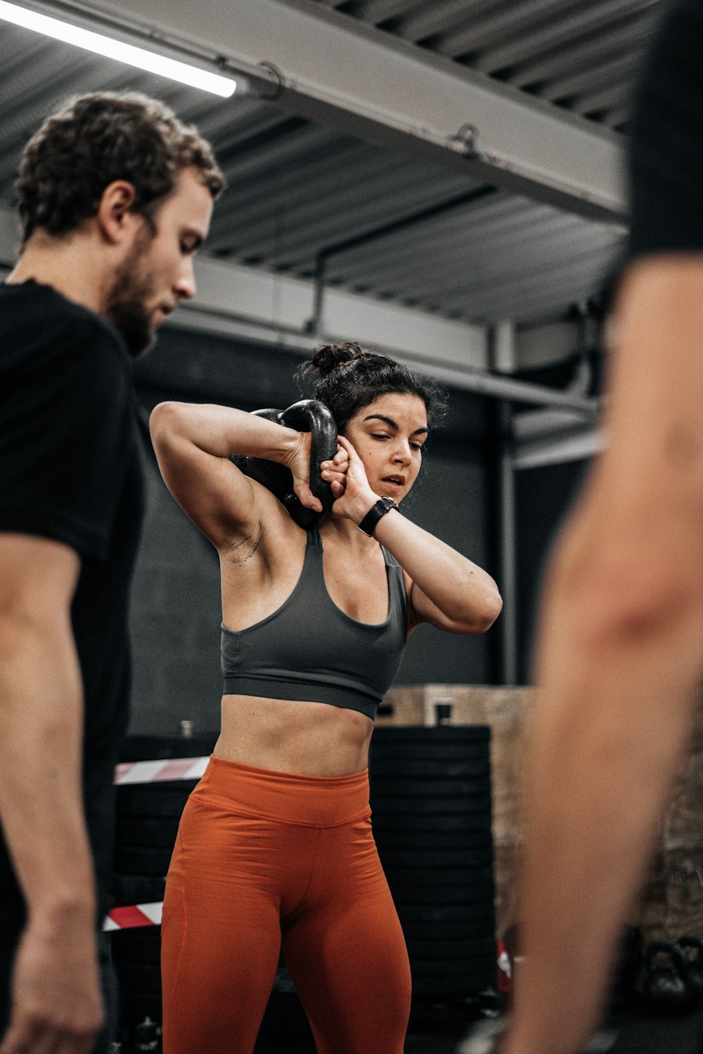 a woman in a black sports bra top and orange leggings