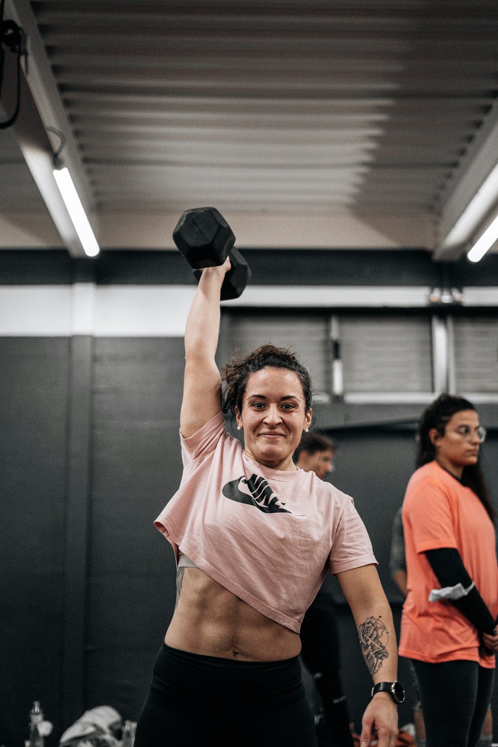 a woman lifting a black dumbbell in a gym