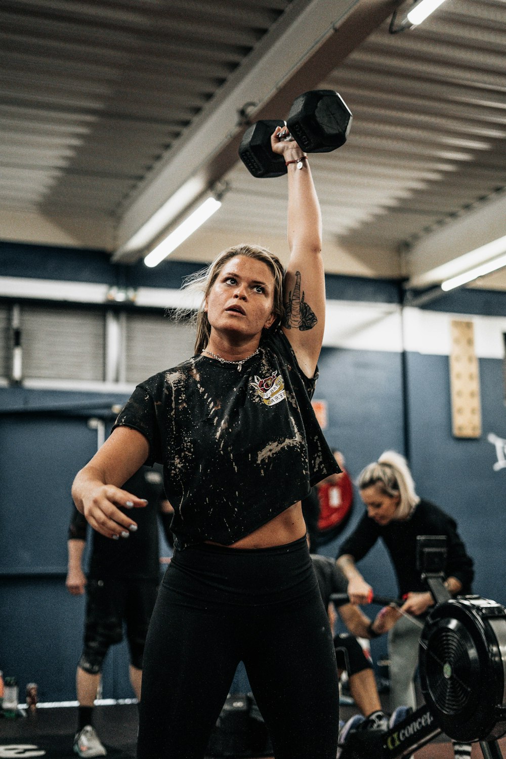 A woman holding a pair of dumbs in a gym photo – Strenght Image on Unsplash