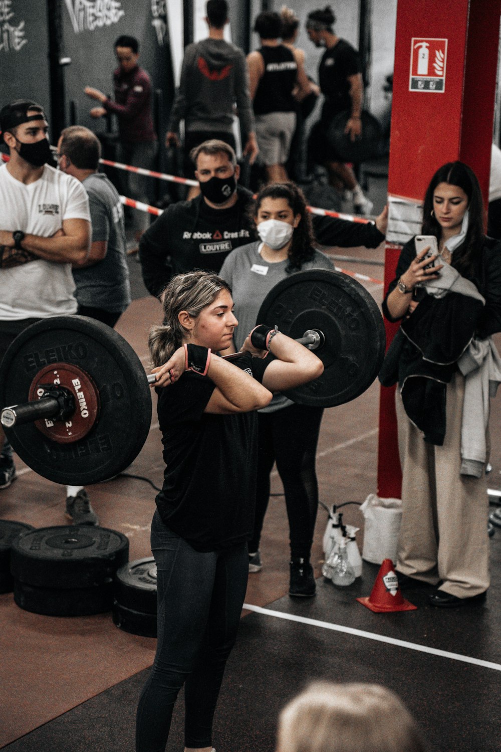 a woman holding a barbell in front of a group of people