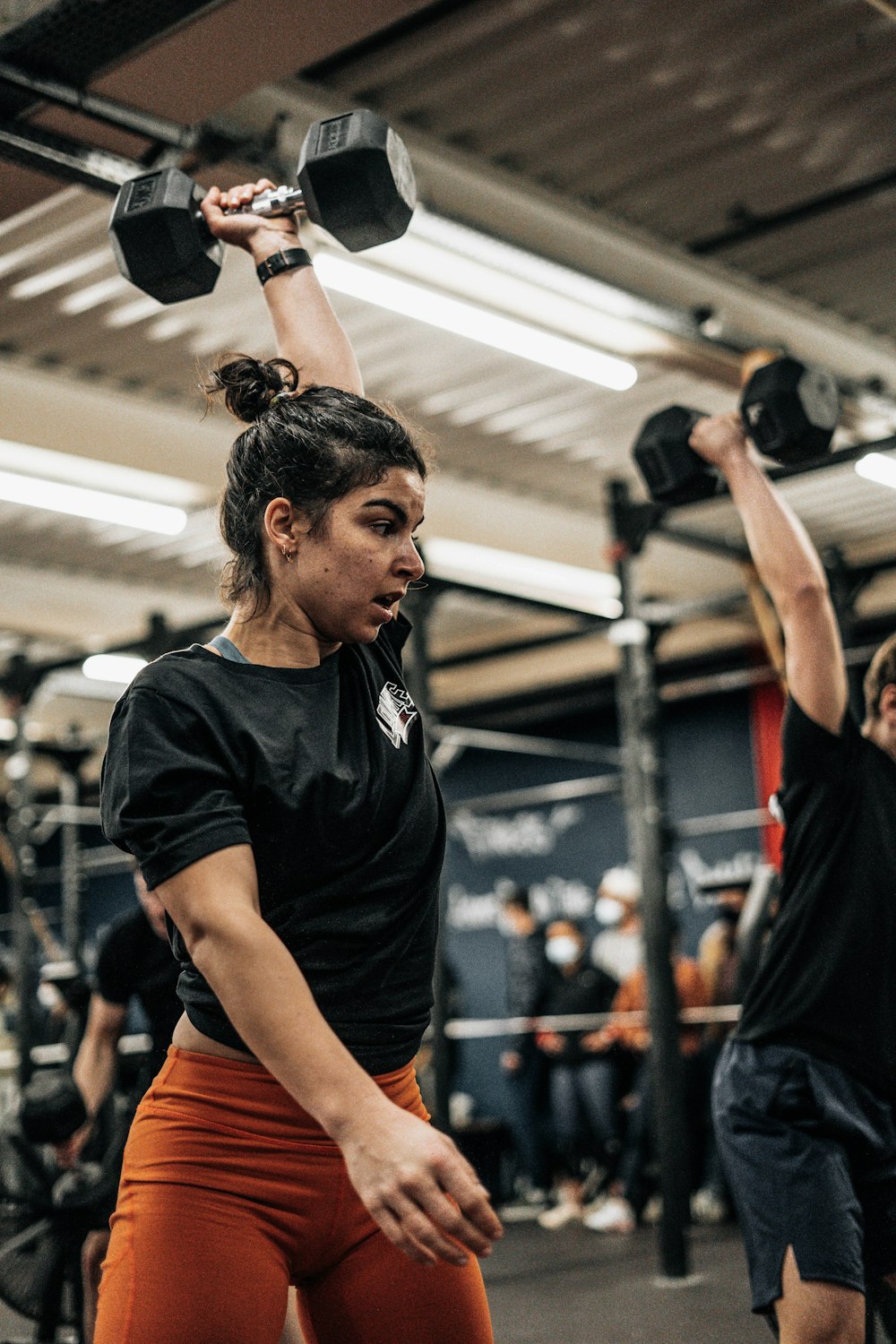 a woman lifting two dumbs in a gym