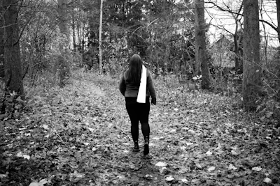 Author walking through a quiet forest path with a thoughtful expression