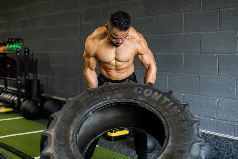 Un homme debout à côté d’un pneu dans un gymnase