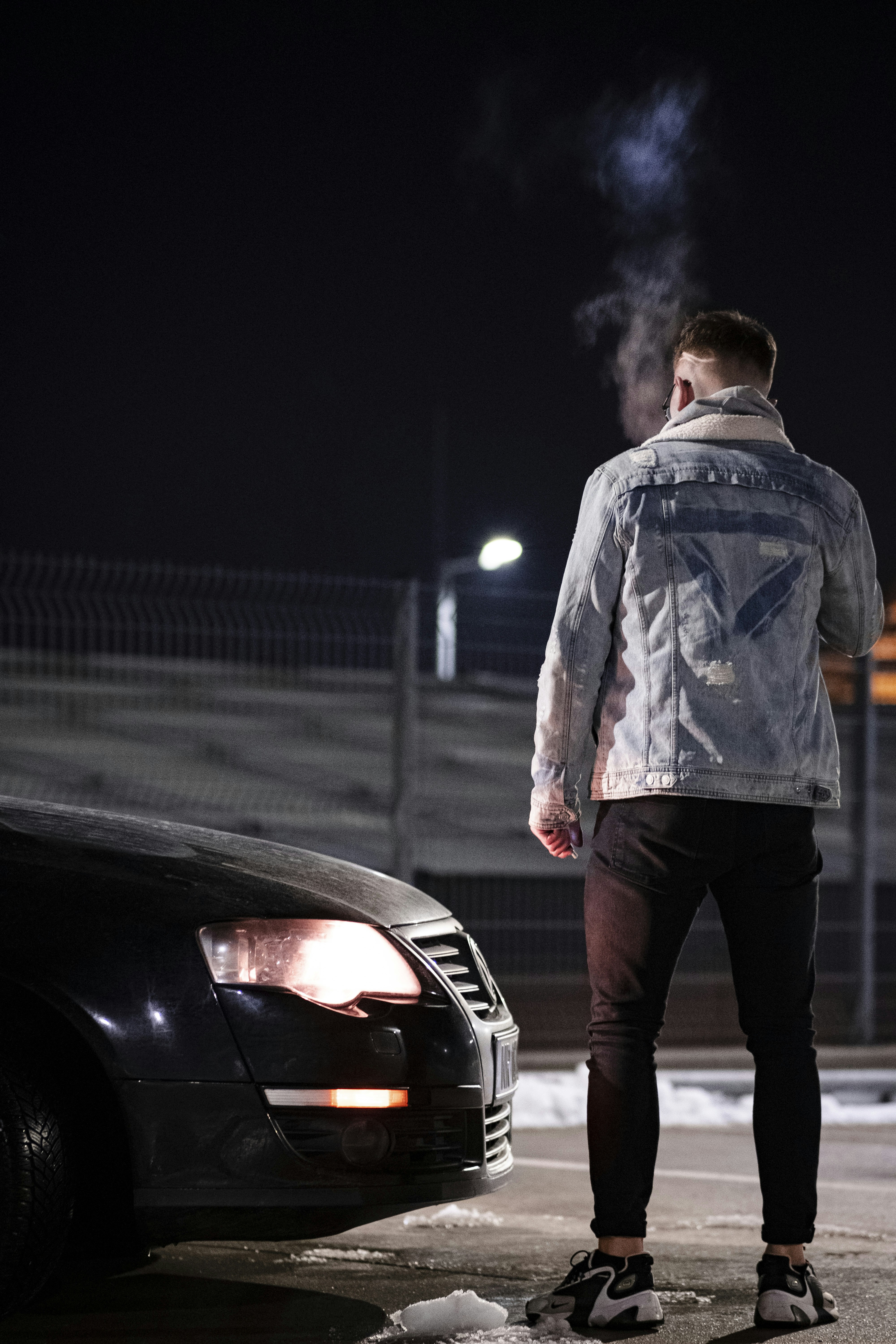 A man standing next to a car with smoke coming out of it