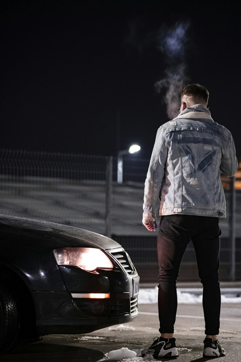 um homem de pé ao lado de um carro com fumaça saindo dele