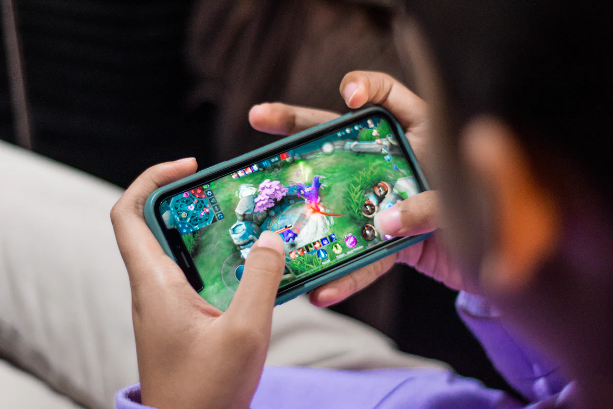 Person playing a competitive game on a mobile phone, focused on the screen