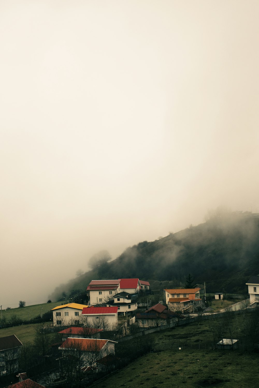 a small village on a hill in the middle of a foggy day
