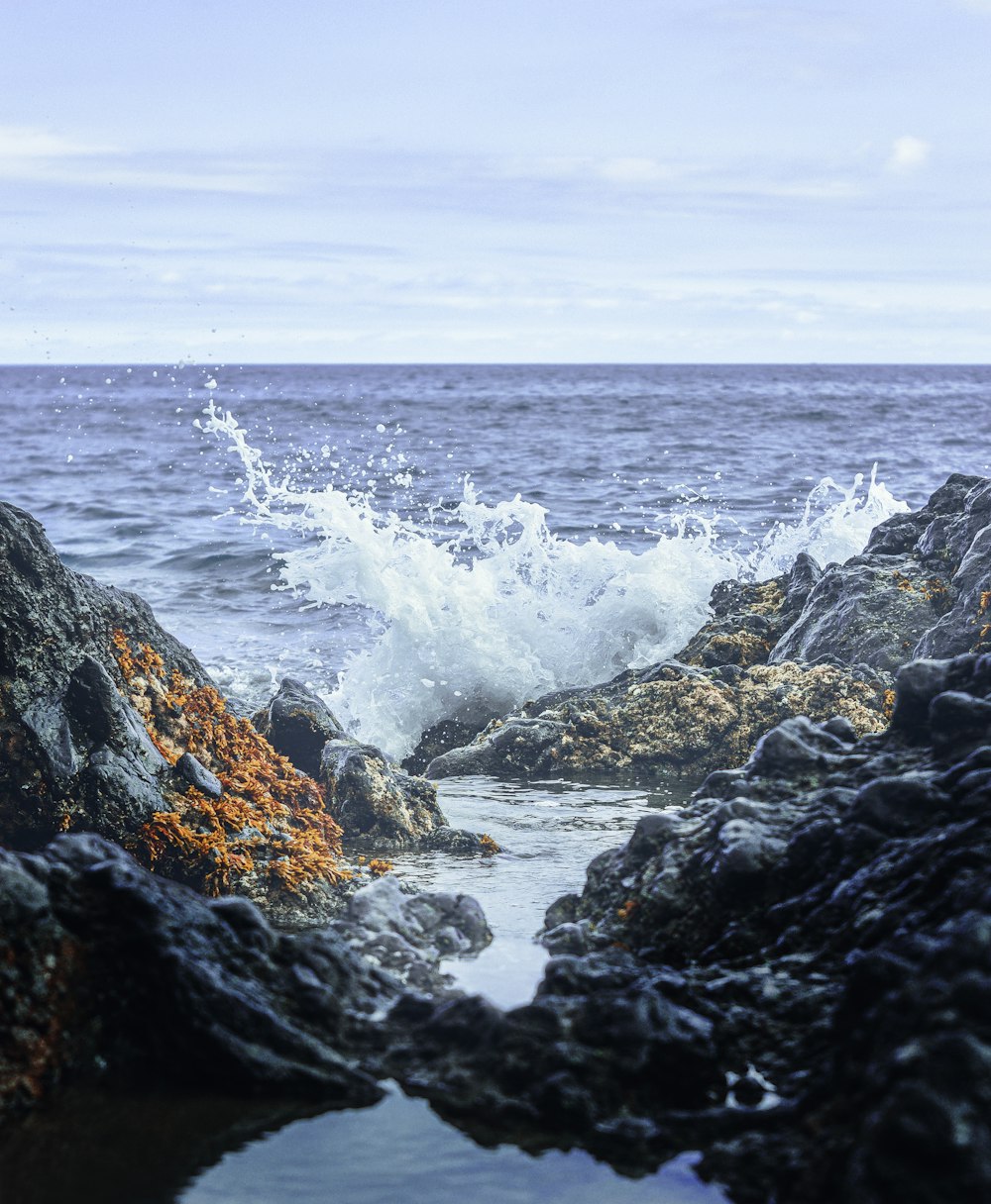 a rock formation with a wave crashing on top of it