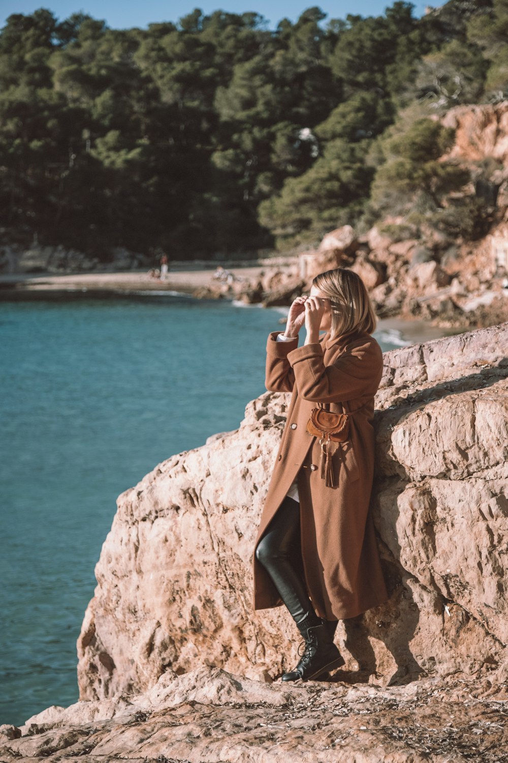 a woman standing on a rock next to a body of water