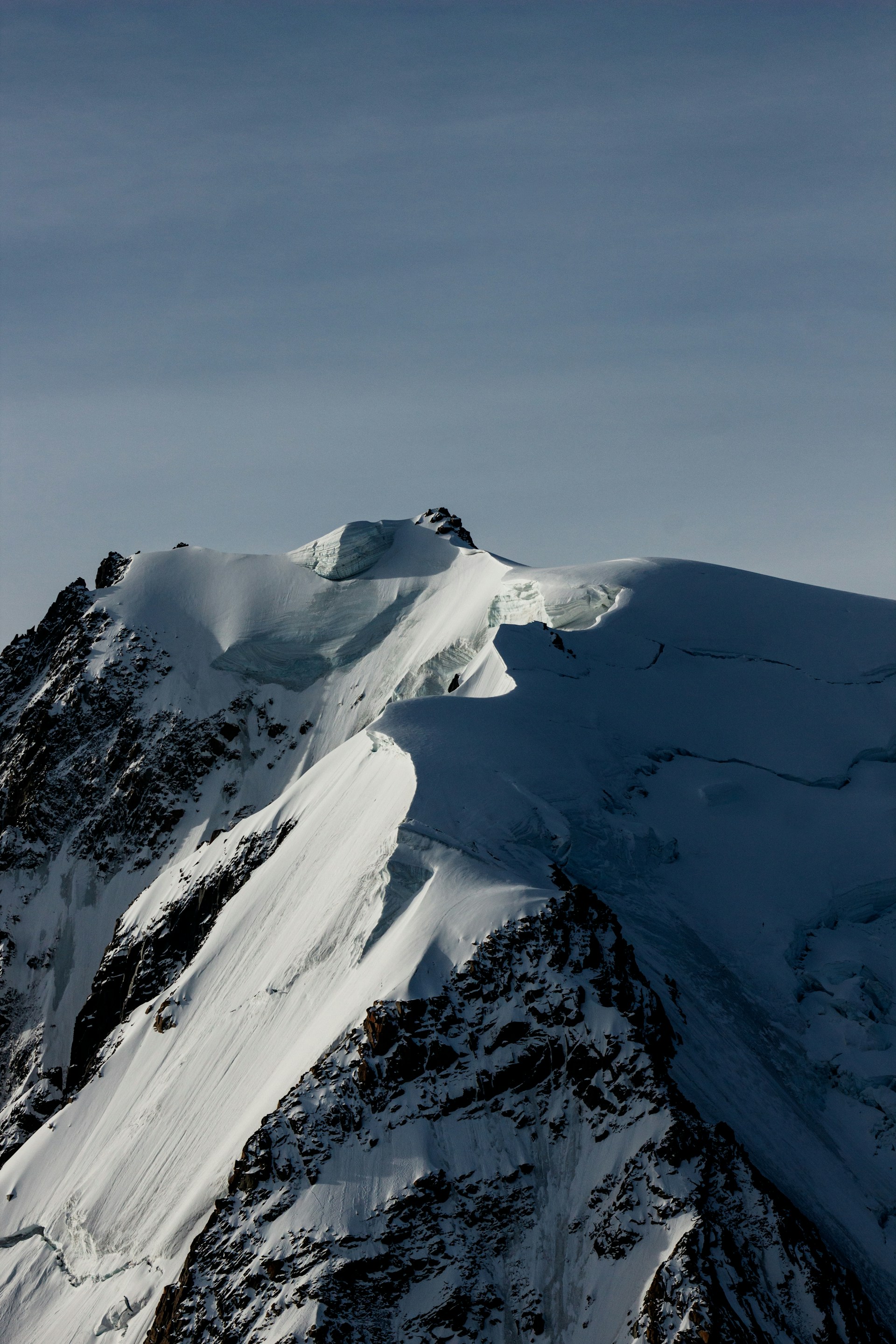 a large mountain covered in snow under a blue sky