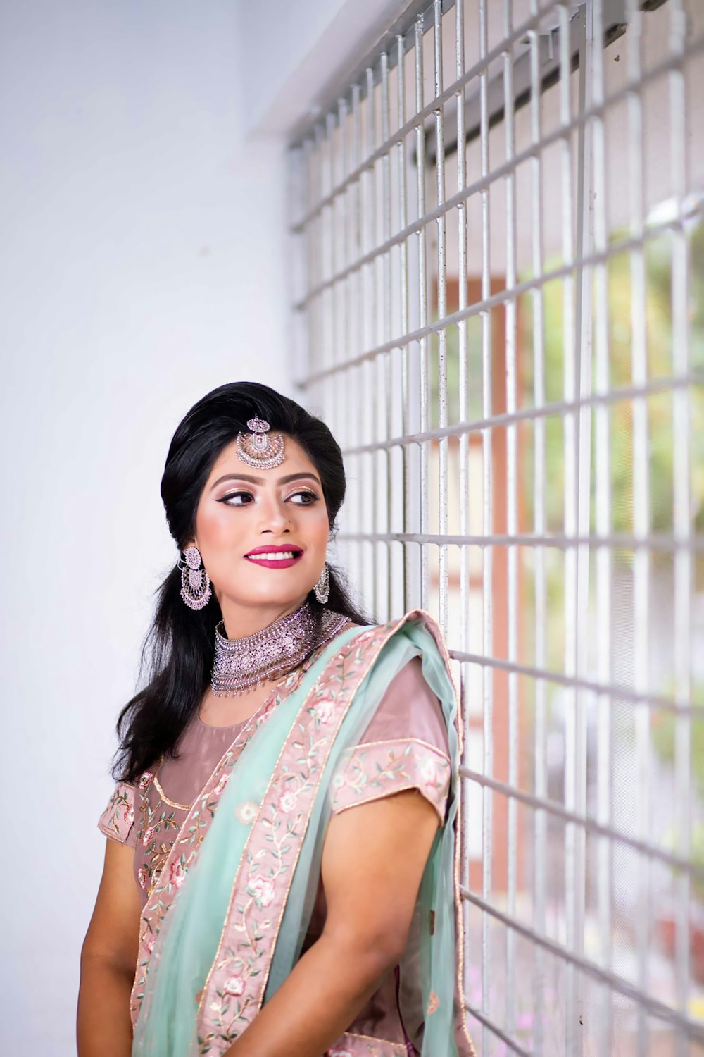 a woman standing next to a window wearing a green sari