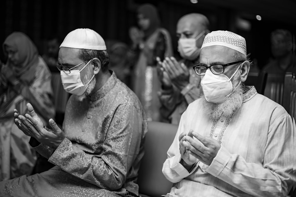 a group of men sitting next to each other wearing face masks