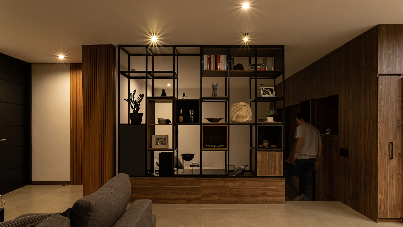 Adult moving through a warm, dark-wood luxury home interior.