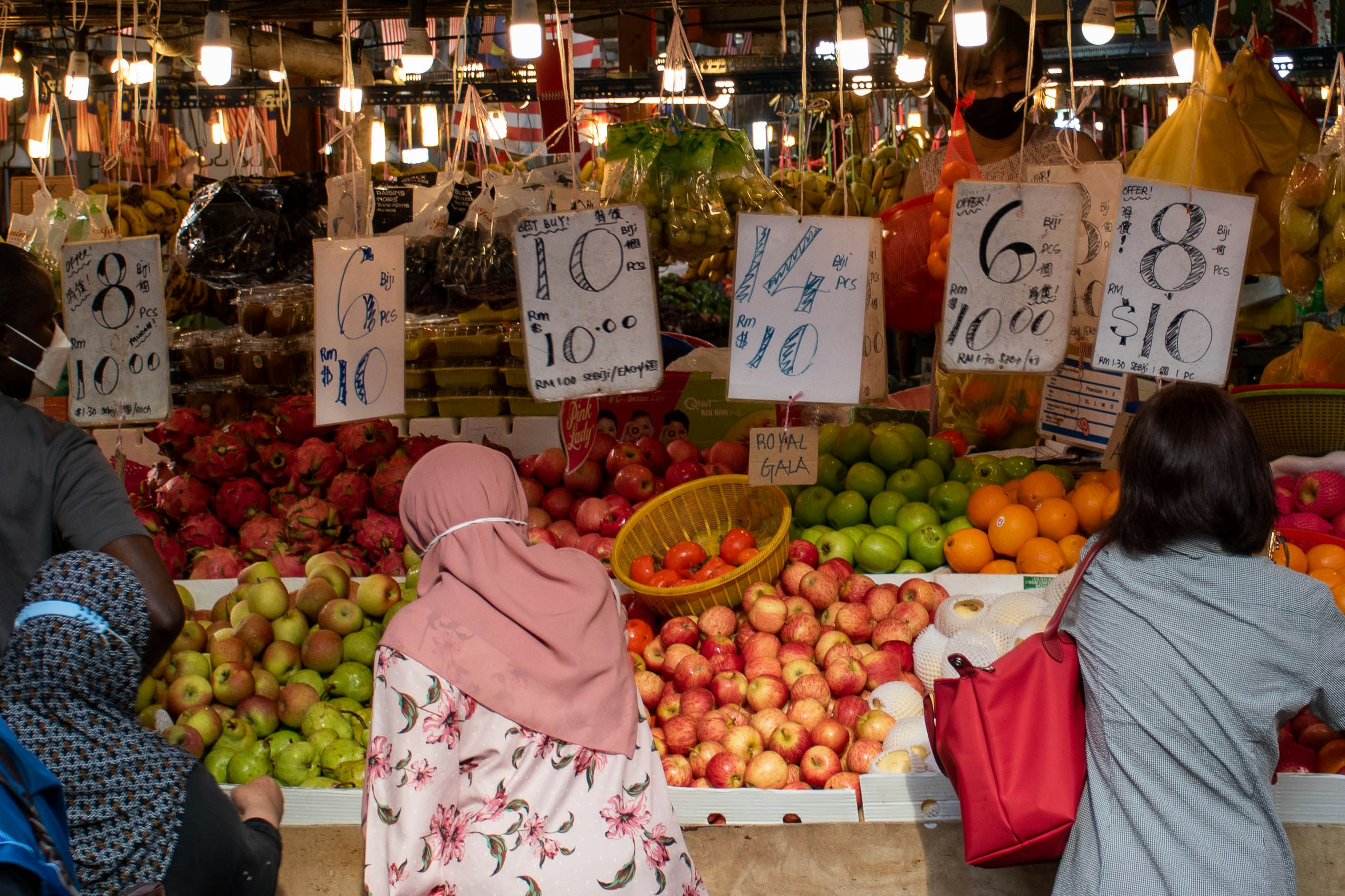 a couple of women standing in front of a fruit stand