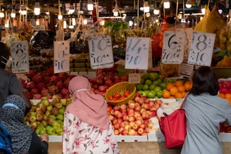 a couple of women standing in front of a fruit stand