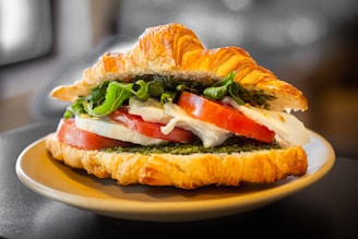a croissant sandwich with tomatoes, cheese, and lettuce
