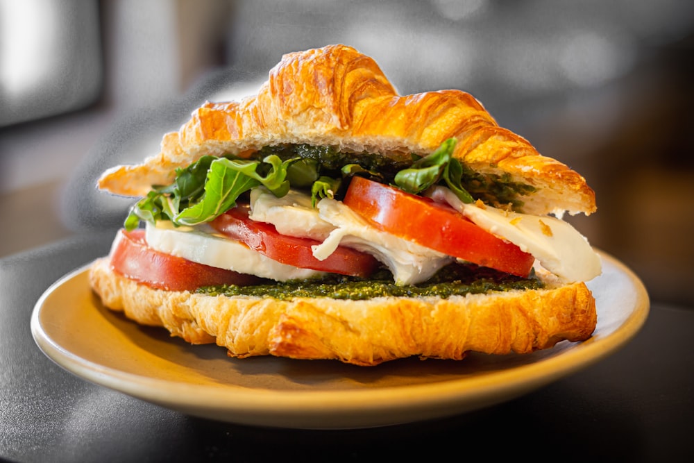 a croissant sandwich with tomatoes, cheese, and lettuce
