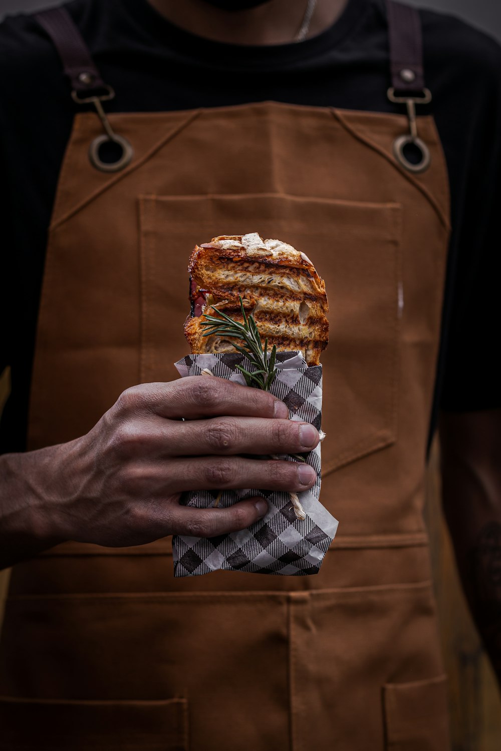 a person holding a sandwich wrapped in paper