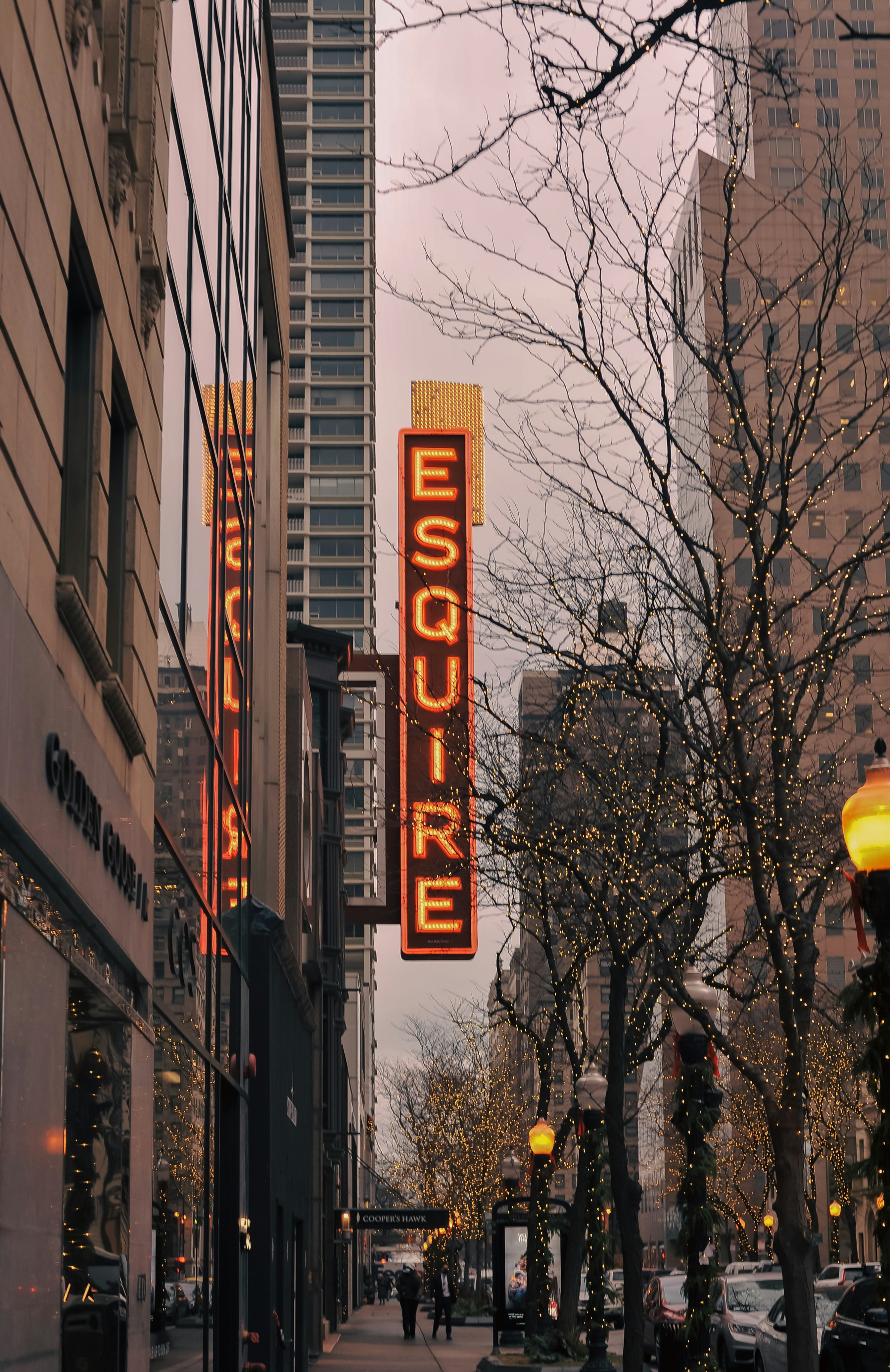 a city street with tall buildings and a neon sign