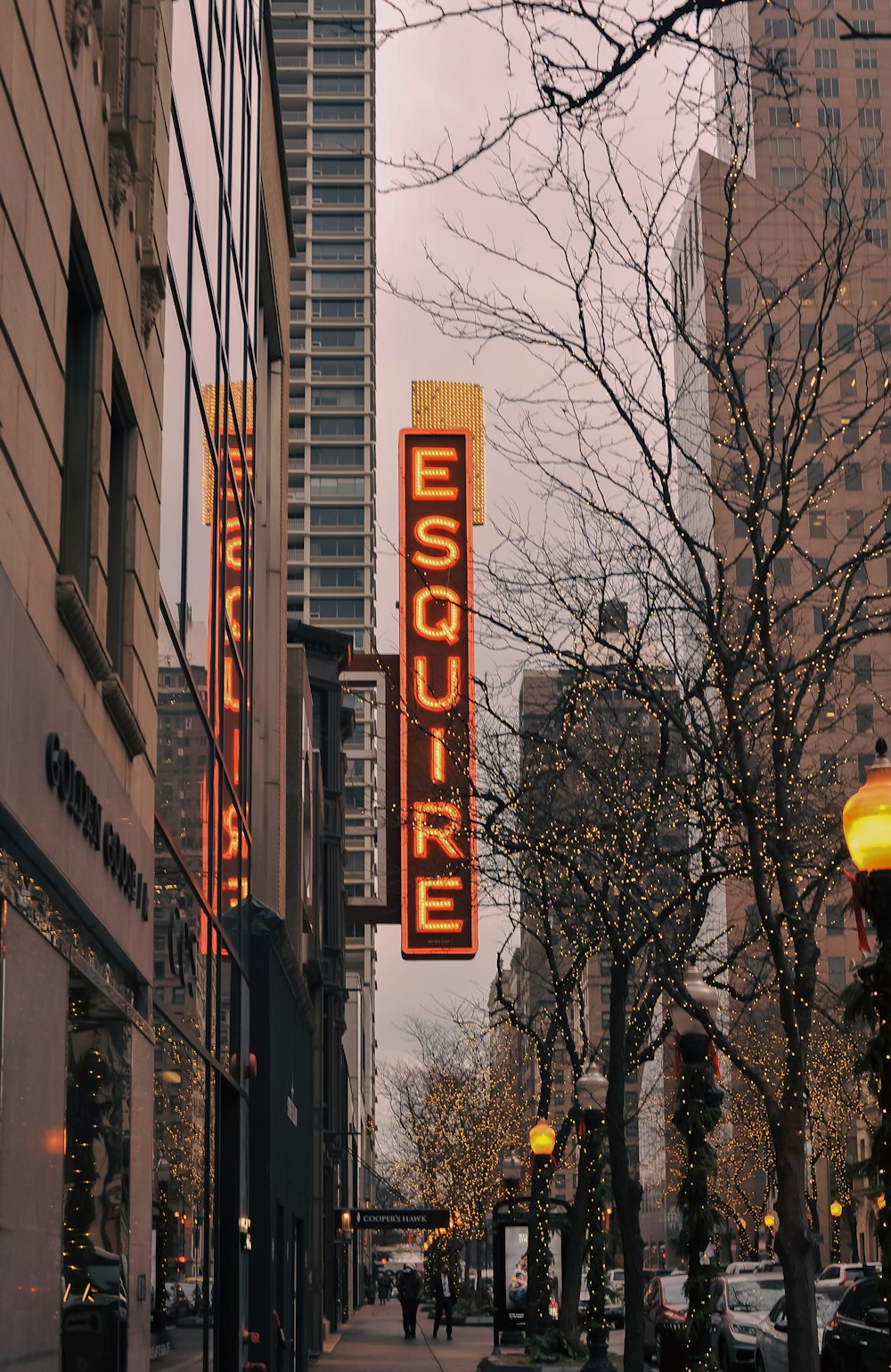 a city street with tall buildings and a neon sign