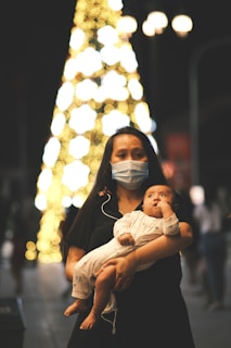 a woman holding a baby wearing a face mask
