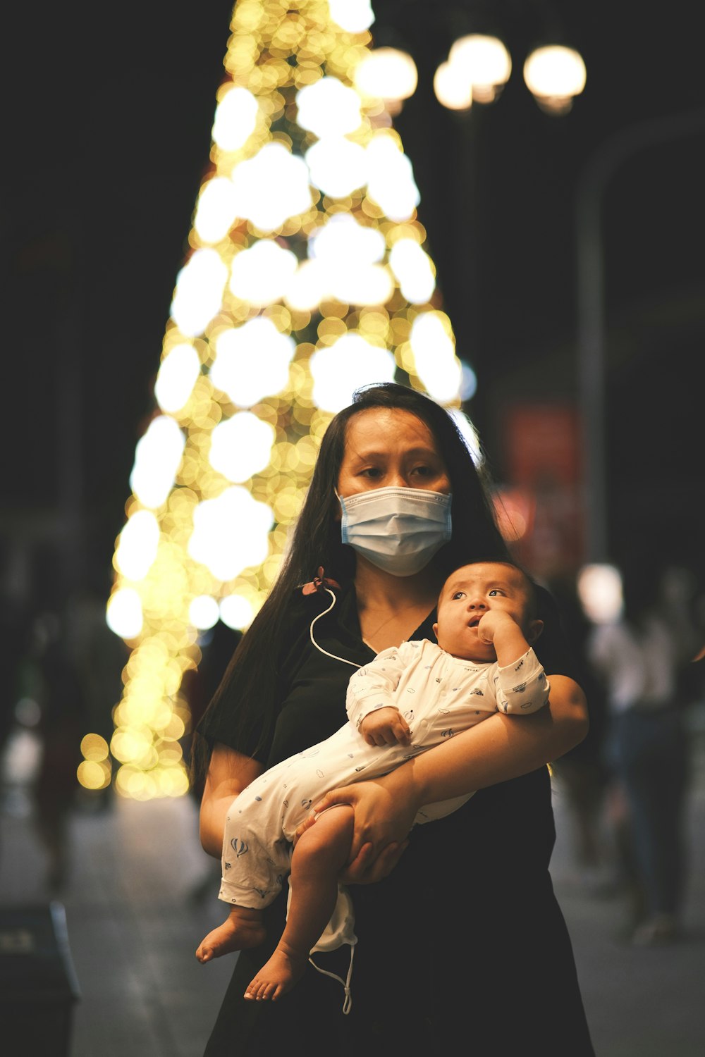 a woman holding a baby wearing a face mask