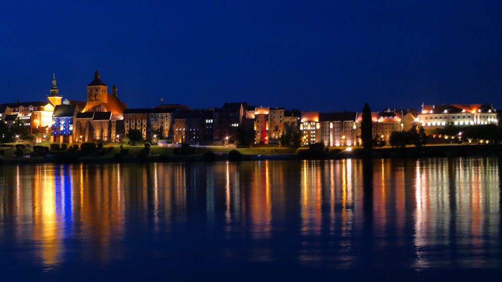 une vue nocturne d’une ville avec un lac devant elle