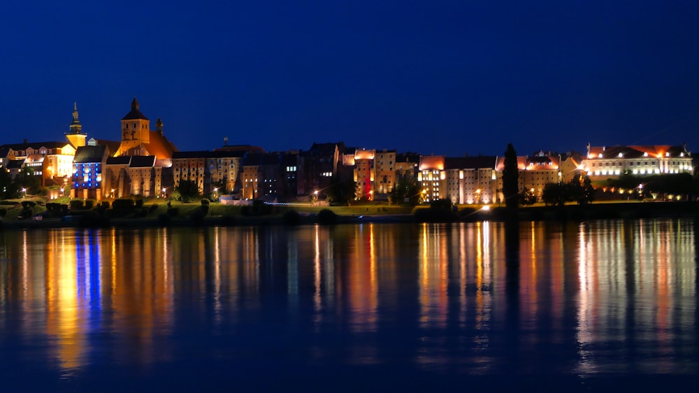 a night view of a city with a lake in front of it