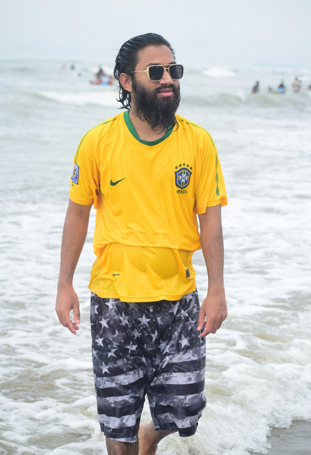 a man in a yellow shirt standing in the ocean