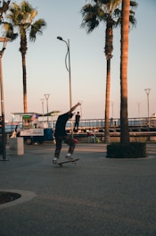 A skate instructor demonstrating tricks on a smooth pavement with palm trees in the background.