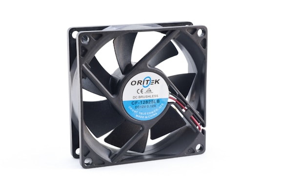 A computer cooling fan that is square in shape with a central rotor and multiple blades. The label on the rotor reads 'Ortek' with model number 'CF-12825LB' and specifications such as 'DC 12V 0.12A'. Connecting wires protrude from the side, indicating it is designed for electronic use.