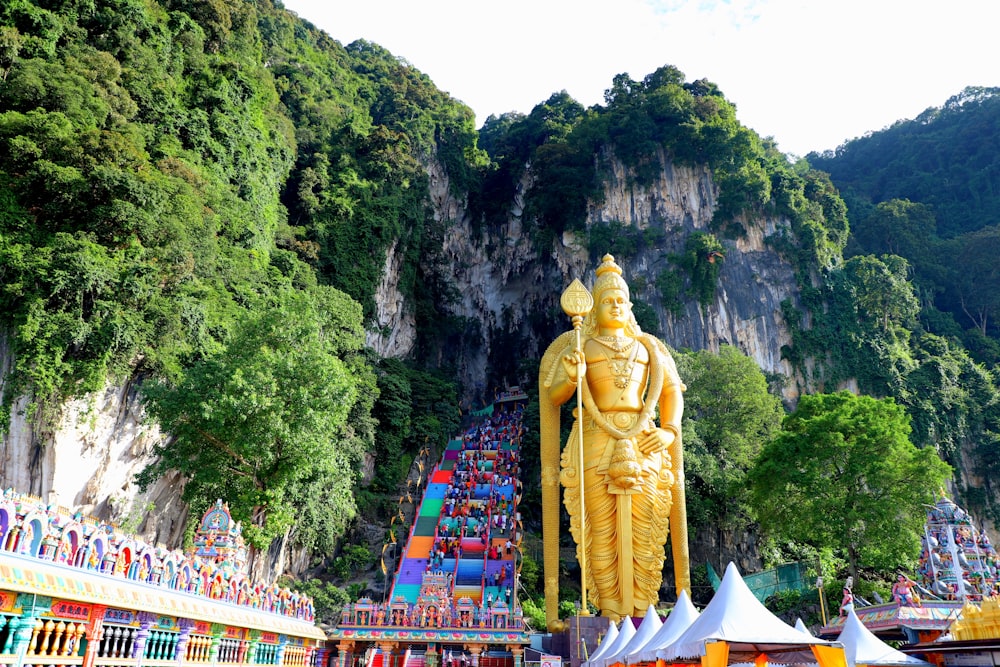a large golden statue sitting in front of a mountain