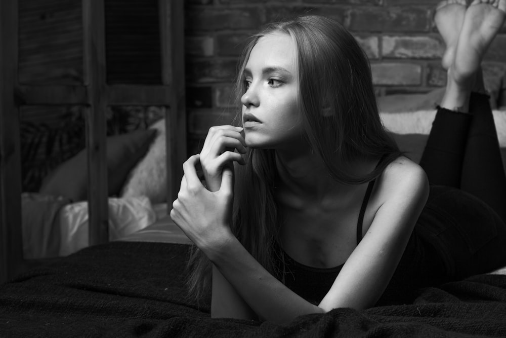 a beautiful young woman laying on top of a bed