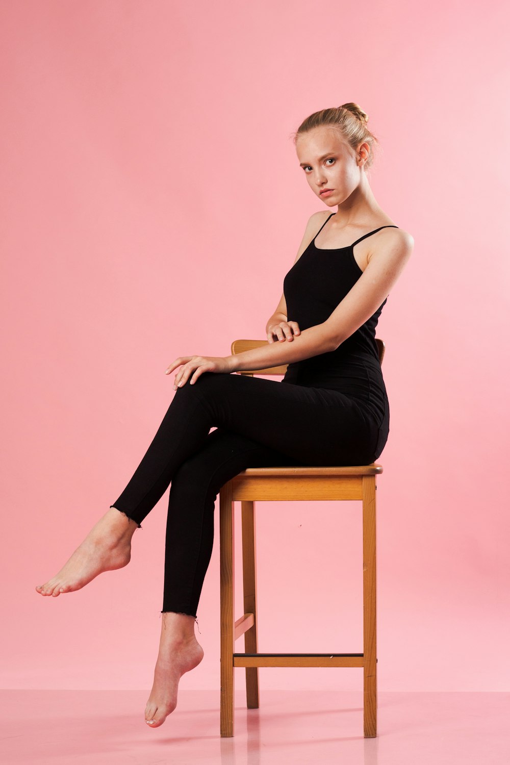 a young girl sitting on a chair with her legs crossed