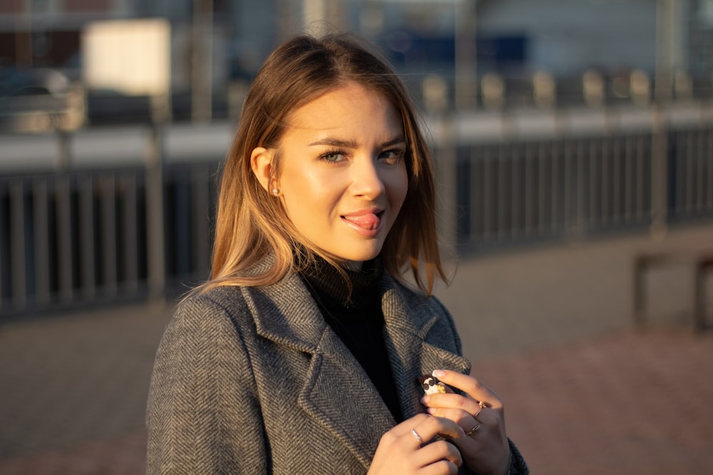 a woman in a coat is holding a cigarette