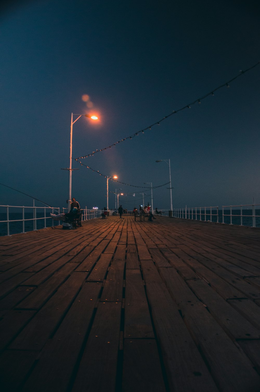 a pier at night with people sitting on benches