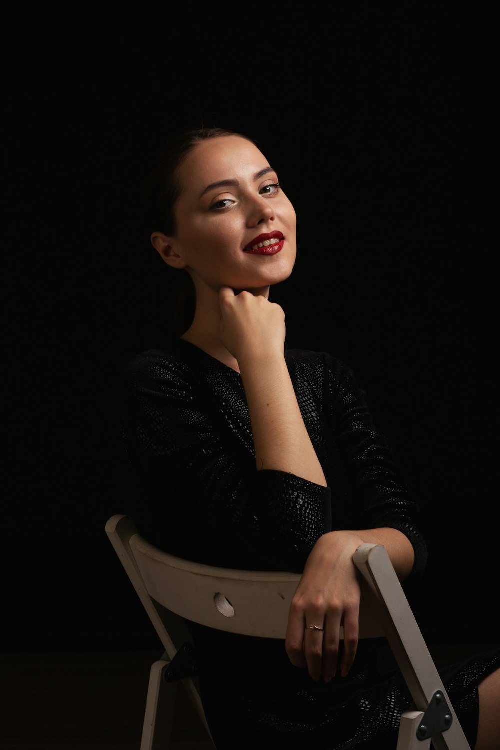 a woman sitting in a chair with her hand on her chin