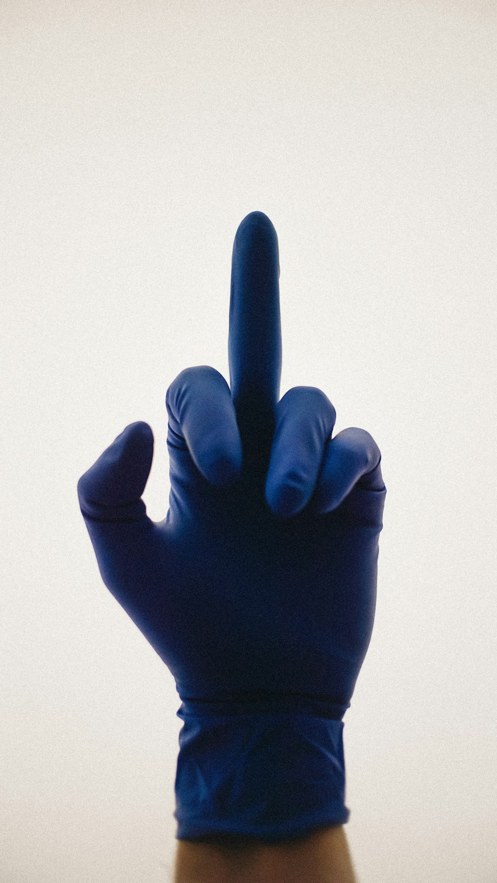 a hand in a blue glove making a peace sign